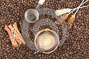 Strong coffee with foam, cinnamon, sugar stick on the coffee beans