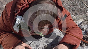 Strong guy with daisies in teeth goes down from steep cliff