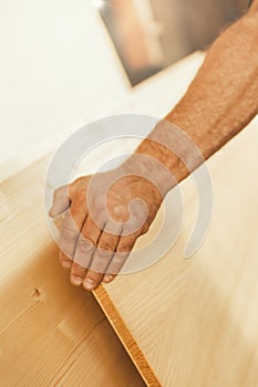 Strong hand lifts large wooden board