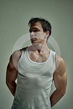 Strong hands. Sportsman. Handsome young man with muscular body posing in singlet over studio background. Concept of