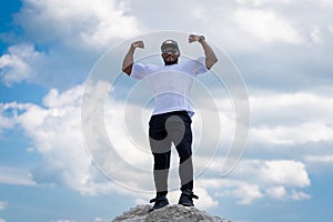 Strong handsome man posing for camera on blue sky. Attractive young lifestyle man.