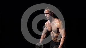 Strong handsome shirtless sport man training biceps with dumbbells on black background