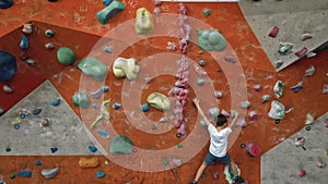 A strong and hardy little boy of 10 years old trains on a climbing wall indoors