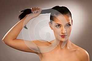 Strong healthy hair - Woman holds a pony tail over gray background