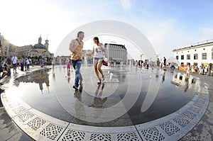 Strong heat in the city: people playing with fountain water jets at the square. Kyiv, Ukraine