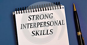 STRONG INTERPERSONAL SKILLS - words in a white notebook on a blue background with a pen