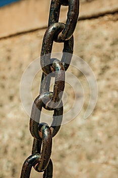 Strong iron chain links in front of stone wall