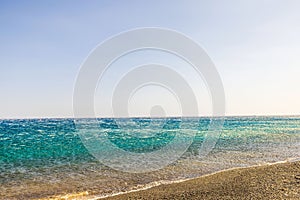 Strong katabatic wind from mountains pushes Aegean sea waves back from shore, creating reverse flow effect under clear sky. photo
