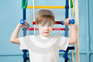 Strong kid boy exercising with dumbbells