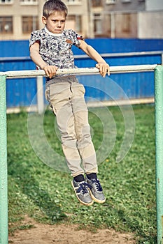 Strong kid doing muscle up on sports ground