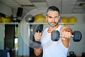 Strong Latin man doing dumbbell punches at a gym.