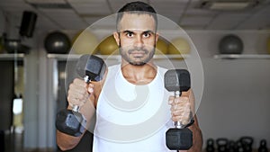 Strong Latin man doing dumbbell punches at a gym.