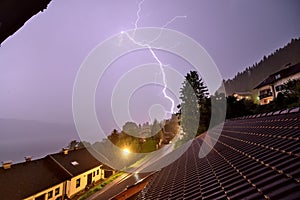 Strong lightning strike at night in the mountains of Austria during a heavy thunderstorm.