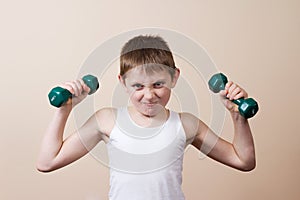 Strong little boy looking at camera while exercising with dumbb