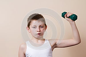 Strong little boy looking at camera while exercising with dumbb