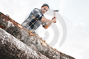 Strong lumberjack in plaid shirt chops tree in wood with sharp ax, close up axe, wood chips fly