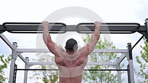 strong male athlete doing pull ups on crossbar outdoors workout training sport activity