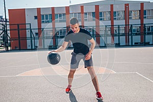 Strong male basketball player preparing for a basketball game on a sunny day wearing a black tee and grey shorts