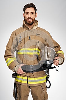 Strong male firefighter in uniform with helmet in studio.