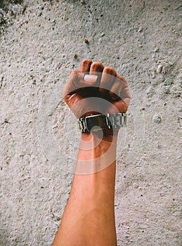 Strong male fist wearing a watch in a concrete background for texts and quotes photo