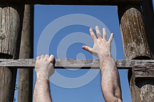 Strong male hands firm gripping wooden ladder step, hanging