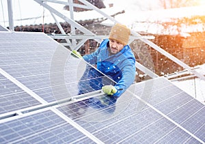 Strong male technician in blue suit installing photovoltaic blue solar modules as renewable energy source.