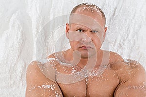 A strong man with big muscles with snow on body in