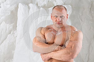 A strong man with big muscles with snow on body in