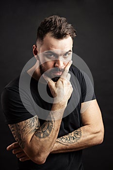 Strong man in black tight fitted shirt with a serious expression on his face.