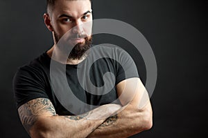 Strong man in black tight fitted shirt with a serious expression on his face.