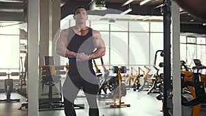 Strong man bodybuilder posing and shows muscles near mirror in the gym