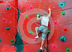 Strong man climbing on a climbing wall