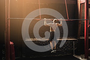 Strong man doing pull up exercise in the gym