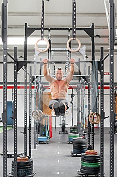Strong man doing pull ups on bar in fitness club