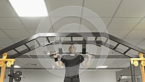 Strong man doing pull ups in a gym