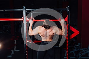 Strong man doing pull ups handsome athlete at gym. big confident muscular training.