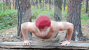 Strong man doing push ups in forest. Male sportsman exercising at nature. Young guy training outdoor. Muscular athlete