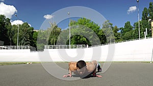 Strong man doing push ups in outdoor street gym.