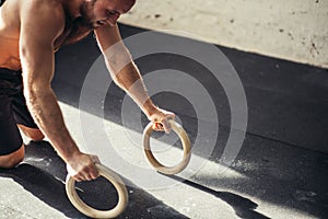 Strong man is doing push-ups by rings.