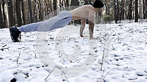 Strong man doing push ups on snow at winter forest. Sportsman exercising at nature. Young guy training outdoor. Muscular