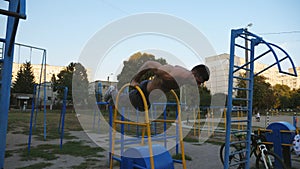 Strong man doing push ups on sports equipment at playground. Young sportsman exercising at sports ground. Muscular