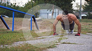 Strong man doing push ups at sports ground. Young sportsman exercising outdoor. Muscular athlete showing hard and