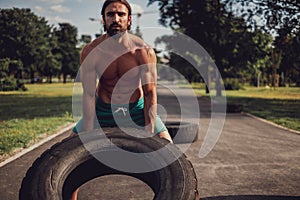 Strong man flipping tires in the park