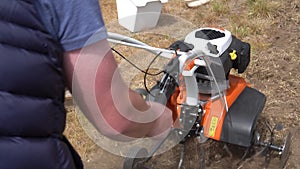 Strong man hands working with petrol cultivator on plowing townhouse yard