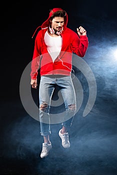 Strong man jumping, wear red hoodie over black background