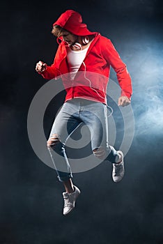 Strong man jumping, wear red hoodie over black background