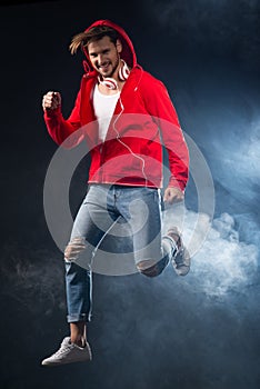 Strong man jumping, wear red hoodie over black background