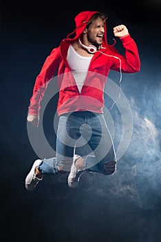 Strong man jumping, wear red hoodie over black background