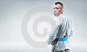 Strong man in a kimono looks over his shoulder. Concept of karate, sambo, jujitsu