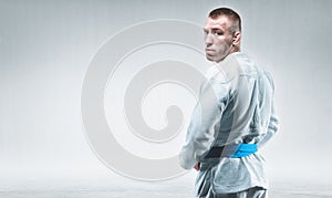 Strong man in a kimono looks over his shoulder. Concept of karate, sambo, jujitsu photo